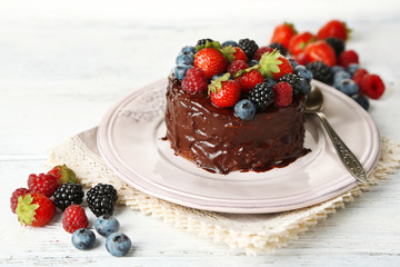 Tasty chocolate cake with different berries, on wooden table