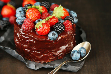 Tasty chocolate cake with different berries on wooden table