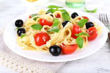 Spaghetti with tomatoes, olives and basil leaves