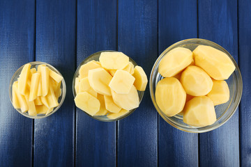Raw peeled and sliced potatoes in glass bowls