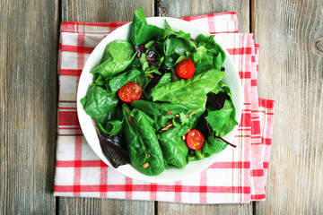 Fresh green salad in bowl on wooden table