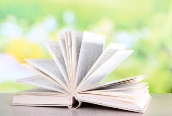 Open book on wooden table on natural background