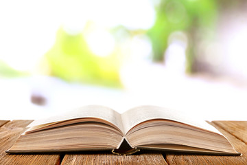 Open book on wooden table on natural background