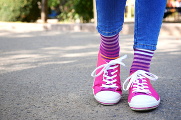 Fototapeta na wymiar Female legs in colorful socks and sneakers outdoors