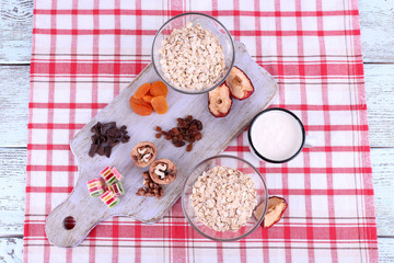 Bowl of oatmeal, mug of yogurt, marmalade, chocolate, raisins,