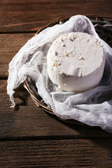 Cottage cheese on gauze on wicker mat on wooden background