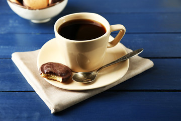 Cup of coffee with tasty cookie on color wooden background