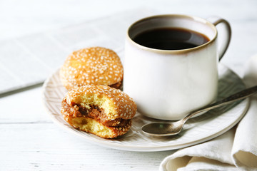 Cup of coffee with tasty cookie on color wooden background