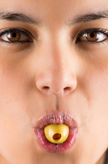 beautiful young latin woman holding olive in her mouth