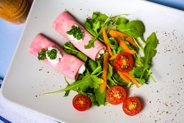 Rolled slices of ham filled with horseradish cream on plate