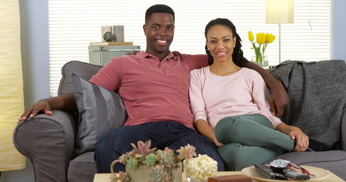 Happy Young Black Couple Relaxing On Couch Looking At Camera