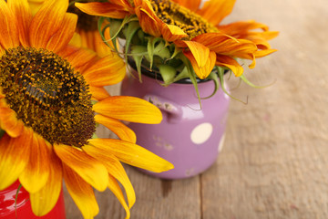 Beautiful sunflowers in cans on wooden background