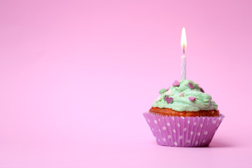 Delicious birthday cupcake on table on pink background