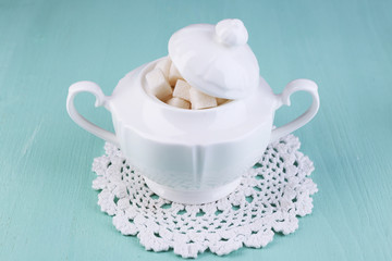 White refined sugar in sugar bowl on color wooden background