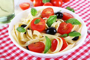 Spaghetti with tomatoes, olives and basil leaves