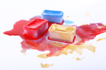 Watercolor paint cubes and spilled paint isolated on white