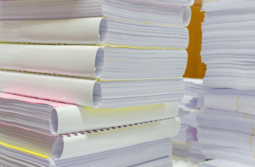 Pile of documents on desk stack up high waiting to be managed