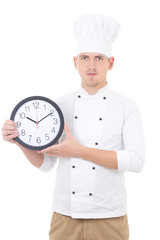 young man chef in uniform showing office clock isolated on white