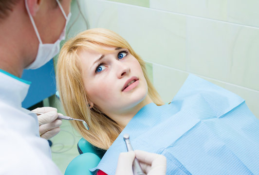 Scared patient at dentist office looking at doctor afraid