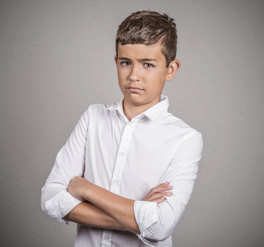 Portrait skeptical teenager boy on grey wall background 