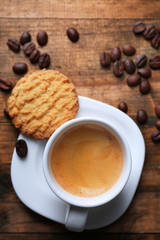 Cup of espresso and tasty cookie on wooden background