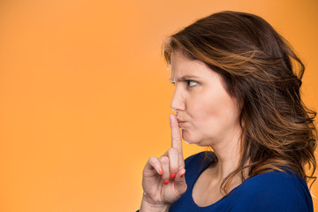 Quiet side profile woman asking to keep secret finger on lips