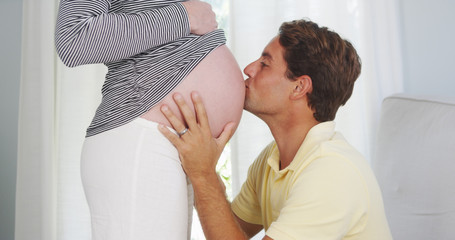 Excited husband kissing pregnant woman's belly