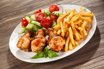 Grilled chicken legs with chips and vegetables