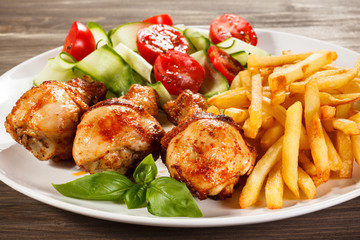 Grilled chicken legs with chips and vegetables