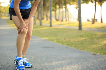 woman runner hold her sports injured legs