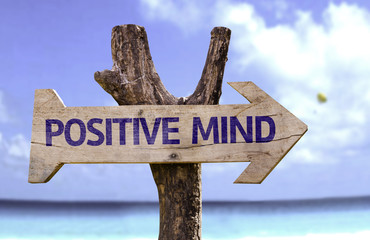 Positive Mind wooden sign with a beach on background