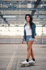 Happy teenager riding skateboard portrait outdoors in a parking