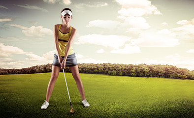 Female golfer with golf club teeing-off on the nature