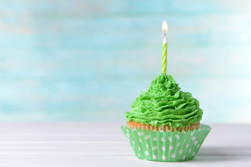 Delicious birthday cupcake on table on light blue background