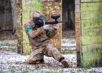 Fototapeta premium Extreme sportsman playing paintball game on first snow