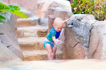 Baby boy playing with water tap outdoors