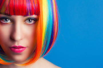 beautiful woman wearing colorful wig against blue background - 72429392