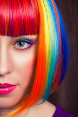 beautiful woman wearing colorful wig against wooden background