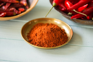 chilli powder in bowl with dried and fresh peppers in background