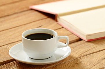a cup of coffee and book on wooden table