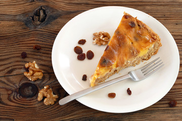piece of cake, some raisins, walnuts and cake fork on an oldwood