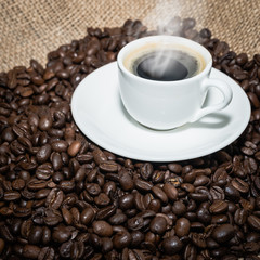 cup of coffee with a smoke and roasted coffee beans