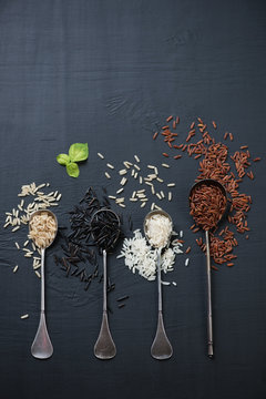 Vintage spoons with red, brown, white and black rice kernels