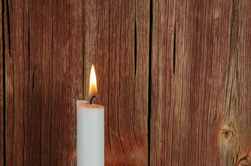Fototapeta na wymiar One burning candle at an old red wall