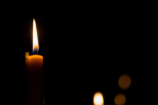Yellow candle on the dark background and bokeh