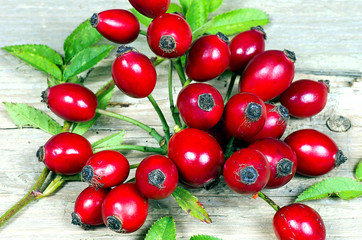 Several Rosehips with leaves on a wooden table