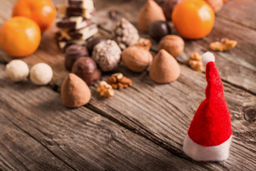 Christmas hat with chocolate and orange on old wooden table