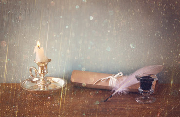 low key image of white Feather, inkwell, and candle and  glitter
