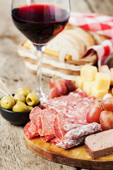 Glass of red wine with charcuterie assortment on the background