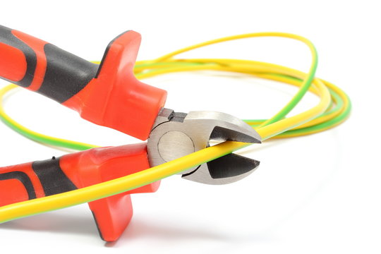 Metal pliers and green-yellow cable on white background